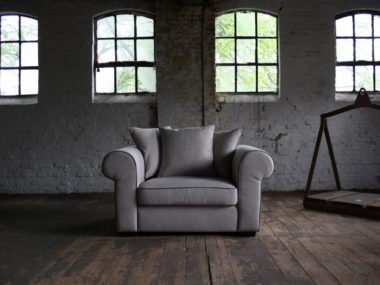 Landelijke fauteuil / loveseat in een grijs beige stof met rugkussens.